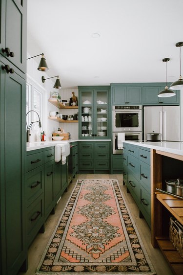 vintage rug for kitchen floor with green cabinets and black fixtures