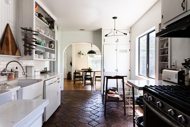 White kitchen cabinets with dark hexagon tile floor and black stove
