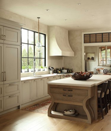 Inviting cream kitchen with custom island with seating and storage with wood floors below.