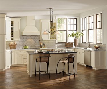 Cheery cream kitchen corner windows, wood floors, rectangular island and barstool seating.