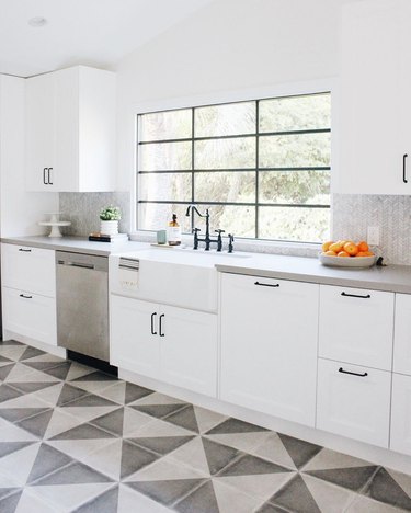 Small gray and white tile herringbone backsplash in modern white kitchen