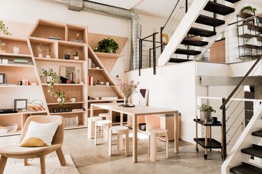 open floor plan living and dining room with light wood furniture and exposed stairs