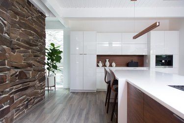 kitchen with white cabinetry and wood accents next to stone wall