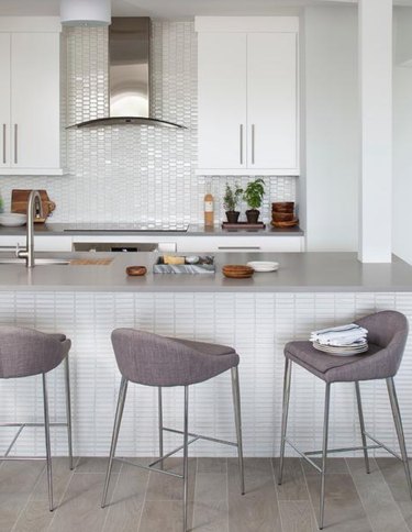 Kitchen with white tile backsplash, white cabinets and gray countertop.