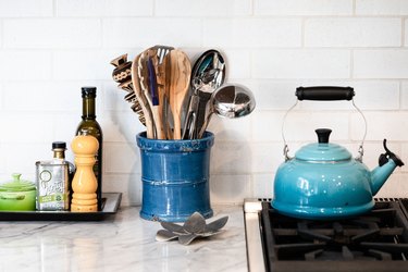 focus on countertop with blue kettle, cooking equipment, spices