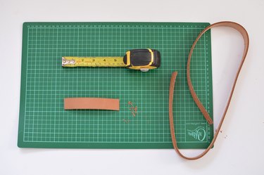 Green cutting mat, measuring tape and leather belt.