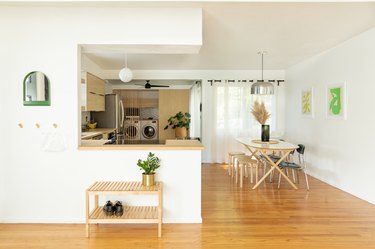 open living area with kitchen, breakfast bar, table, white walls, wood floors