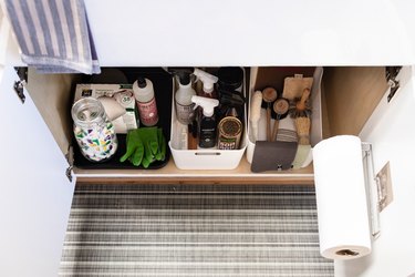 under the sink cabinet featuring organized boxes of cleaning supplies