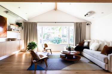 living room with vaulted ceiling, large window, floating credenza