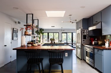 kitchen with blue cabinetry, concrete floors, skylight, windows overlooking trees