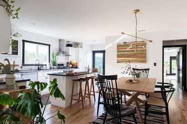 open living and dining room with island, plants, wood table, modern pendant light