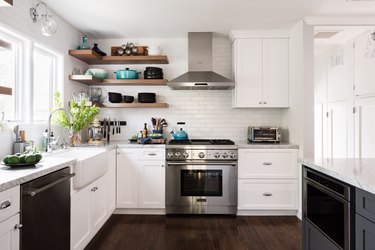 airy kitchen with exposed shelves, dark wood floor, white cabinetry, white tile backsplash