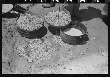 biscuits being made in a Dutch oven over coals with a coal-covered lid being placed on top