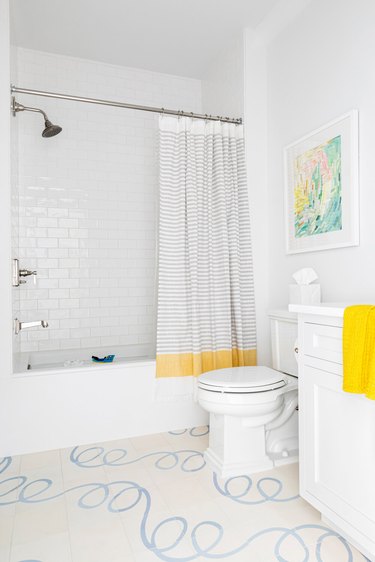 White Bathroom Cabinet with patterned flooring and white subway tile shower by Chango & Co.