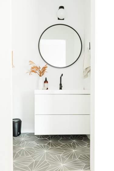 Floating White Bathroom Cabinet with black fixtures and patterned floor tileby Amber Thrane