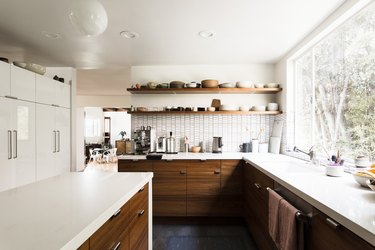 large kitchen with window overlooking trees, wood cabinets and white counter