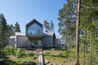 Scandinavian style house in gray color with large window in natural landscape with trees