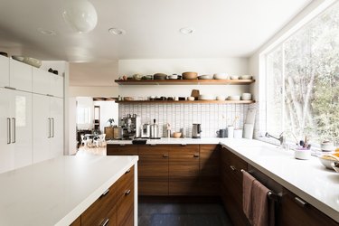 large kitchen with window looking toward trees, dark cabinetry and white counters