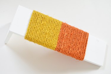 Yellow and orange sisal rope wrapped around white wood for DIY cat scratching post
