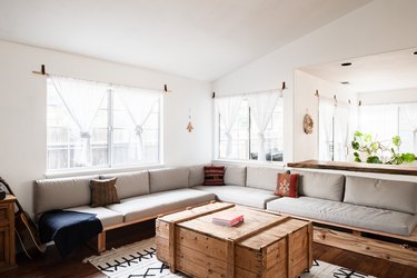 sunny room with L-shaped couch and plants in the background