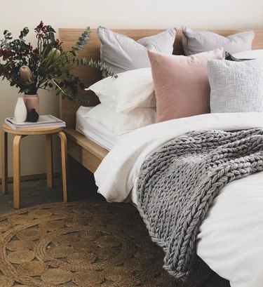 IKEA bed with throw pillows and chunky knit throw