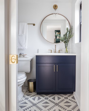 navy blue bathroom cabinets in boho bathroom with patterned tile and white countertop