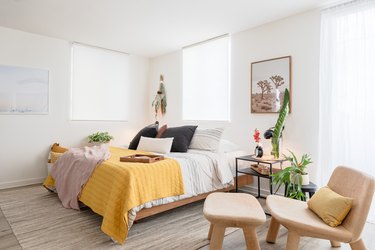 sunny bedroom with bed, windows, chair, yellow quilt