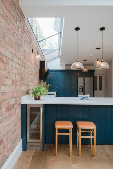 teal kitchen island with exposed brick wall