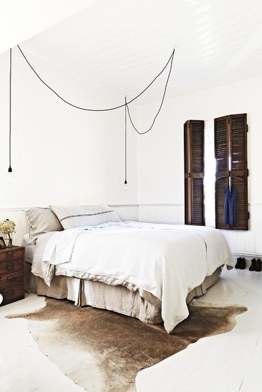 rustic bedroom with suspension lighting and wood shutters