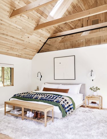 rustic bedroom lighting idea with A-frame ceiling with wood beams and black sconces