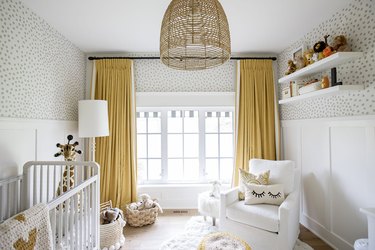 mustard yellow nursery idea with floor to ceiling drapery and patterned wallpaper
