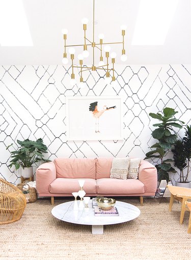living room with comfy pink sofa and pattern wallpaper