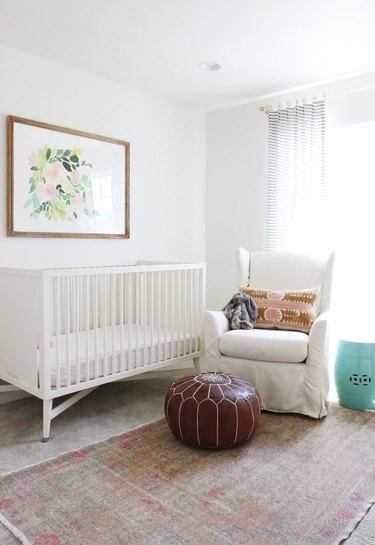 white, pink, and brown nursery idea with upholstered rocking chair and artwork above crib
