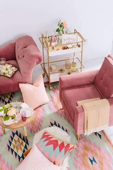 pink living room with velvet lounge chairs and bar cart