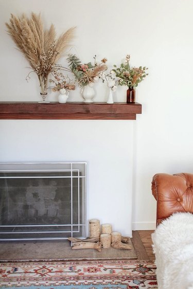 vases full of dried foliage lined up on a wood mantel