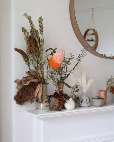 vases full of dried foliage lined up on a white mantel