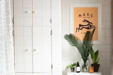 white tile wall in bathroom, close up on plants and poster