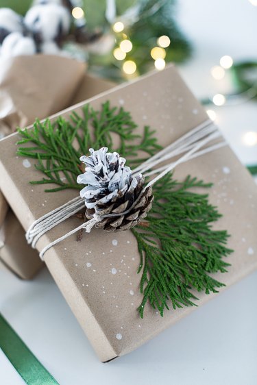Present wrapped with brown paper and a snowy pinecone