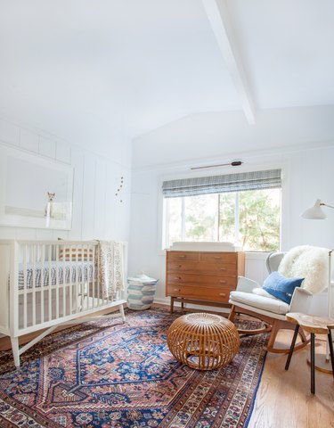 bohemian baby nursery idea with blue and pink kilim rug with lots of wood elements and sheepskin throw