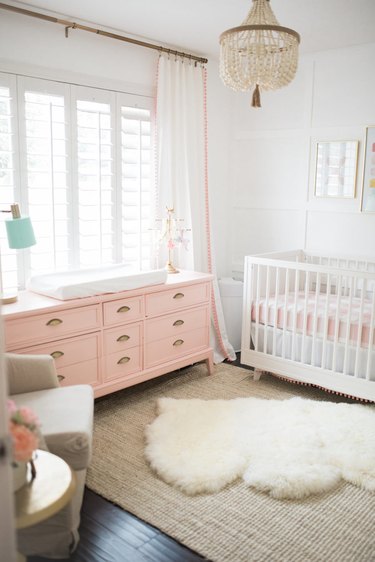 baby nursery idea with pink changing table and crib with floor to ceiling drapery