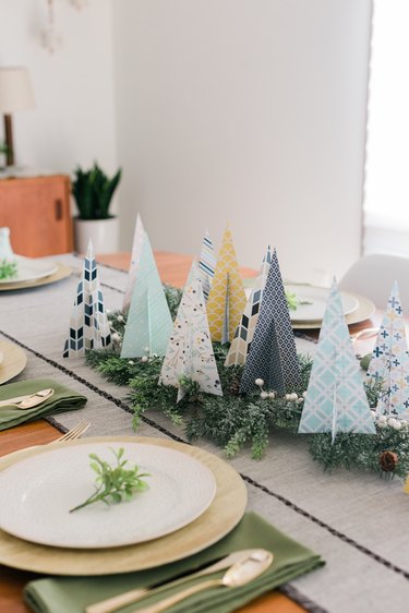 Place the paper Christmas trees on faux evergreen branches to create a centerpiece.