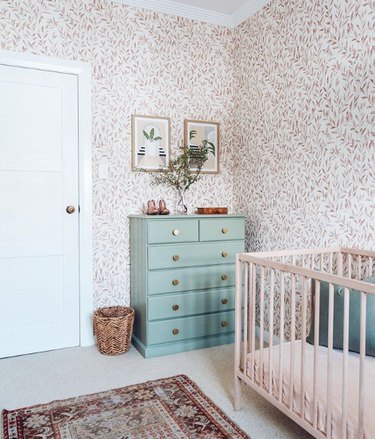 bohemian baby nursery idea with olive branch wallpaper, mint dresser, and natural crib
