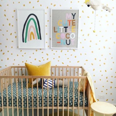 yellow nursery idea with polka dot inspired wallpaper and framed artwork on walls