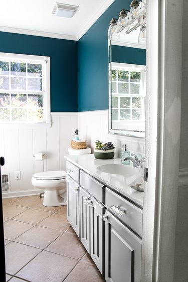 bathroom with teal accent walls and gray cabinet