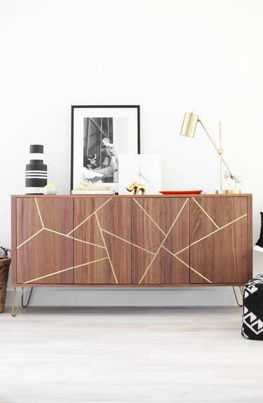 IKEA hack midcentury sideboard with brass inlay detailing topped with artwork and decorative accents