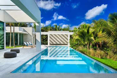 Modern backyard pool design with striped wall reflecting in water