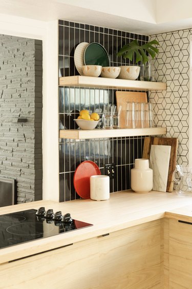 Open shelving in a kitchen with black tile backsplash.