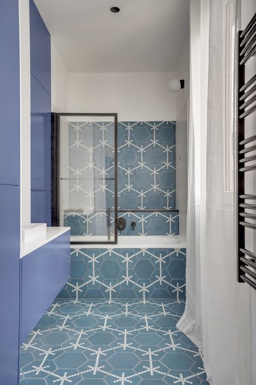 blue and white tile bathroom with black trim glass partition and black shower fixtures
