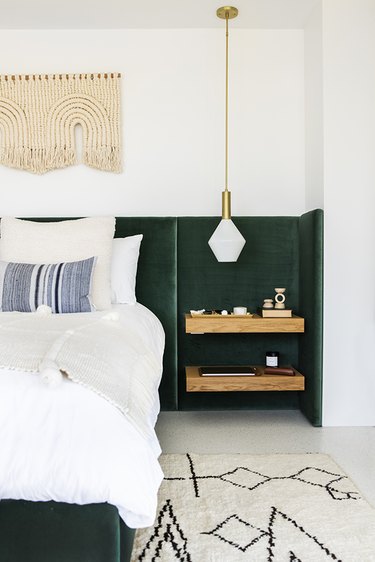 A hunter green upholstered velvet headboard stretches from wall to wall