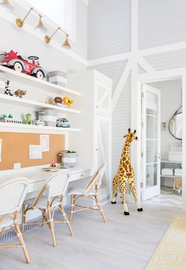 Large kids' bedroom desk area in all-white with farmhouse chairs and children's toys